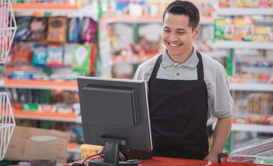 Hombre en caja que brinda servicio al cliente sonríe generando factura